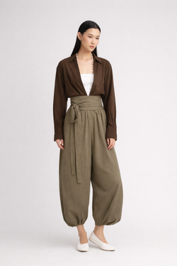 Woman wearing a brown drop-V neckline, relaxed loose-fit long-sleeve top paired with moss-green tobi pants.